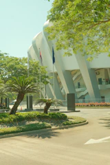 Modern stadium entrance with palm trees and greenery.