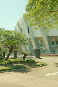 Modern stadium entrance with palm trees and greenery.