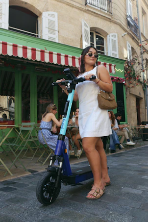 Woman standing with a scooter on a street