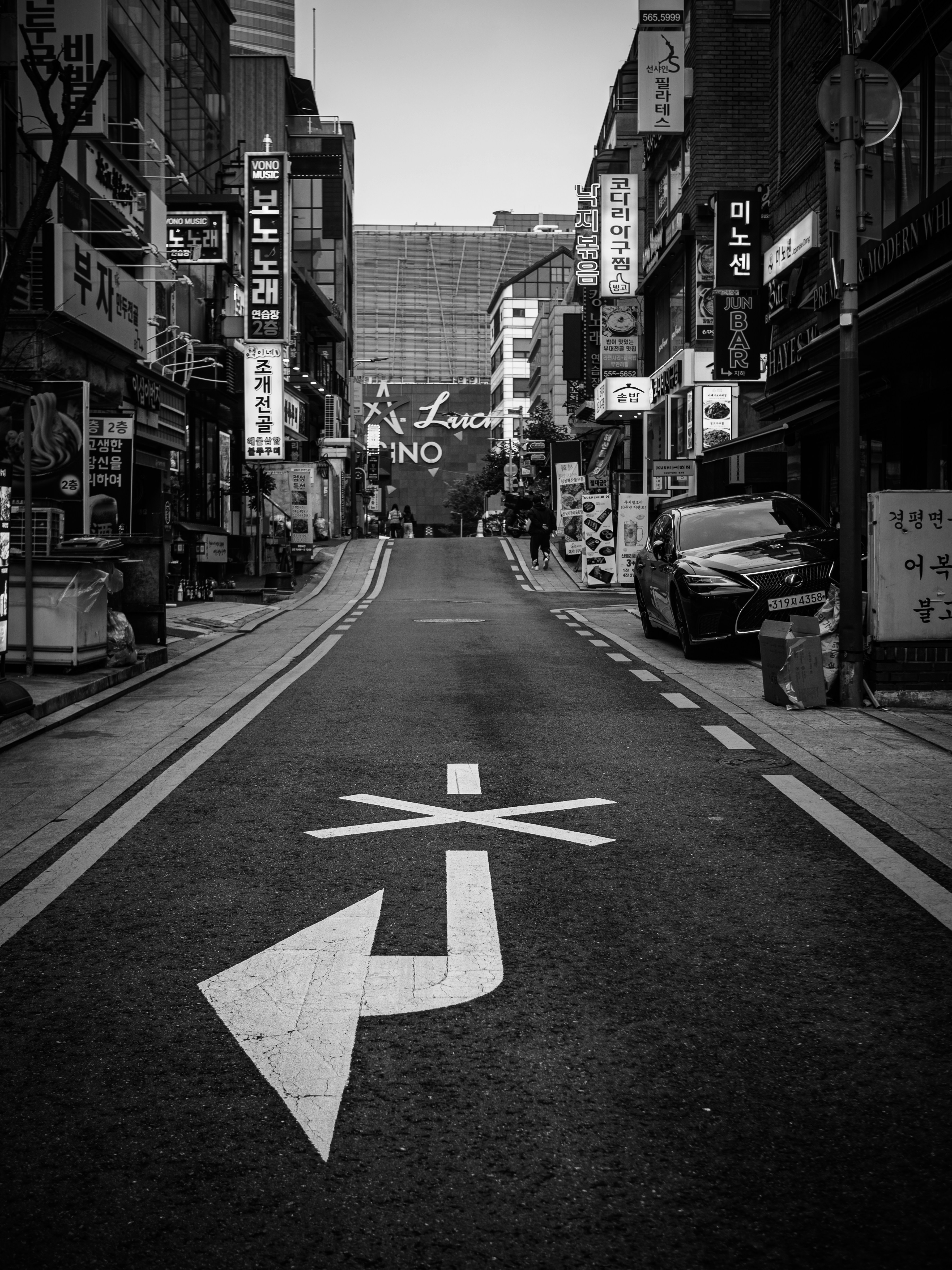 Schwarz-weiße Straßenszene mit Schildern und Auto.