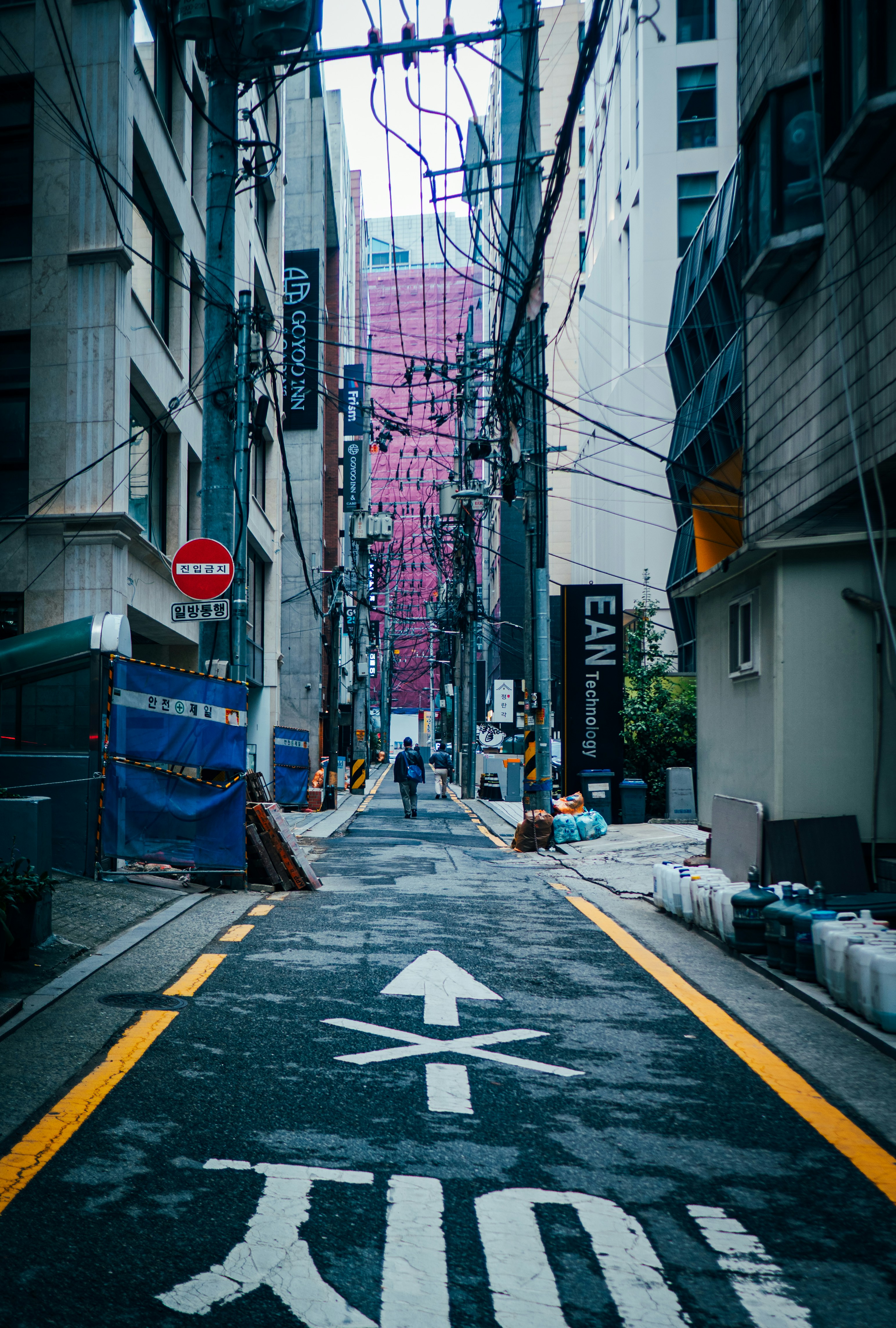 Eine einsame Gestalt geht eine schmale Gasse entlang.