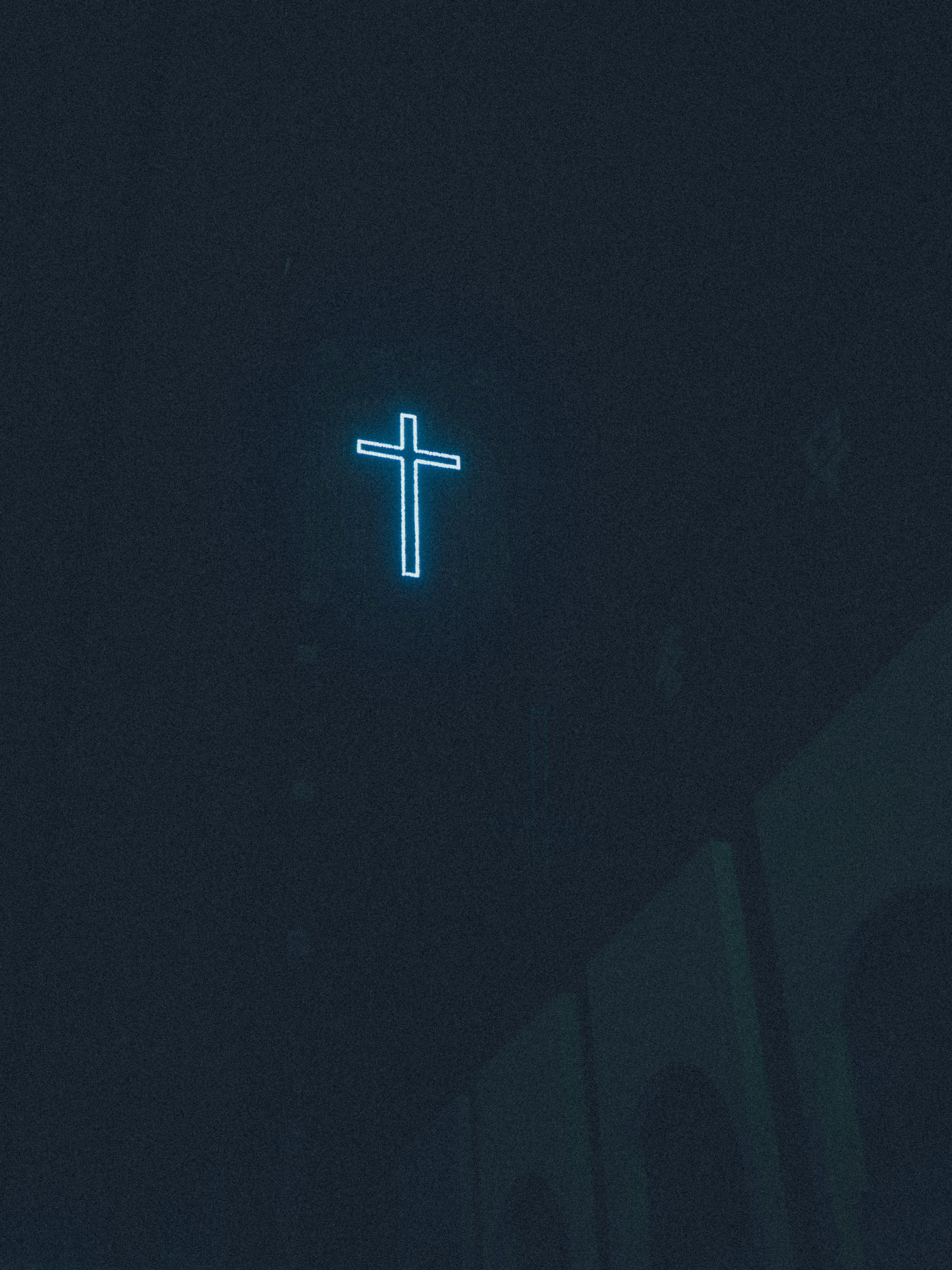 Ein Neonkreuz leuchtet im Dunkeln.