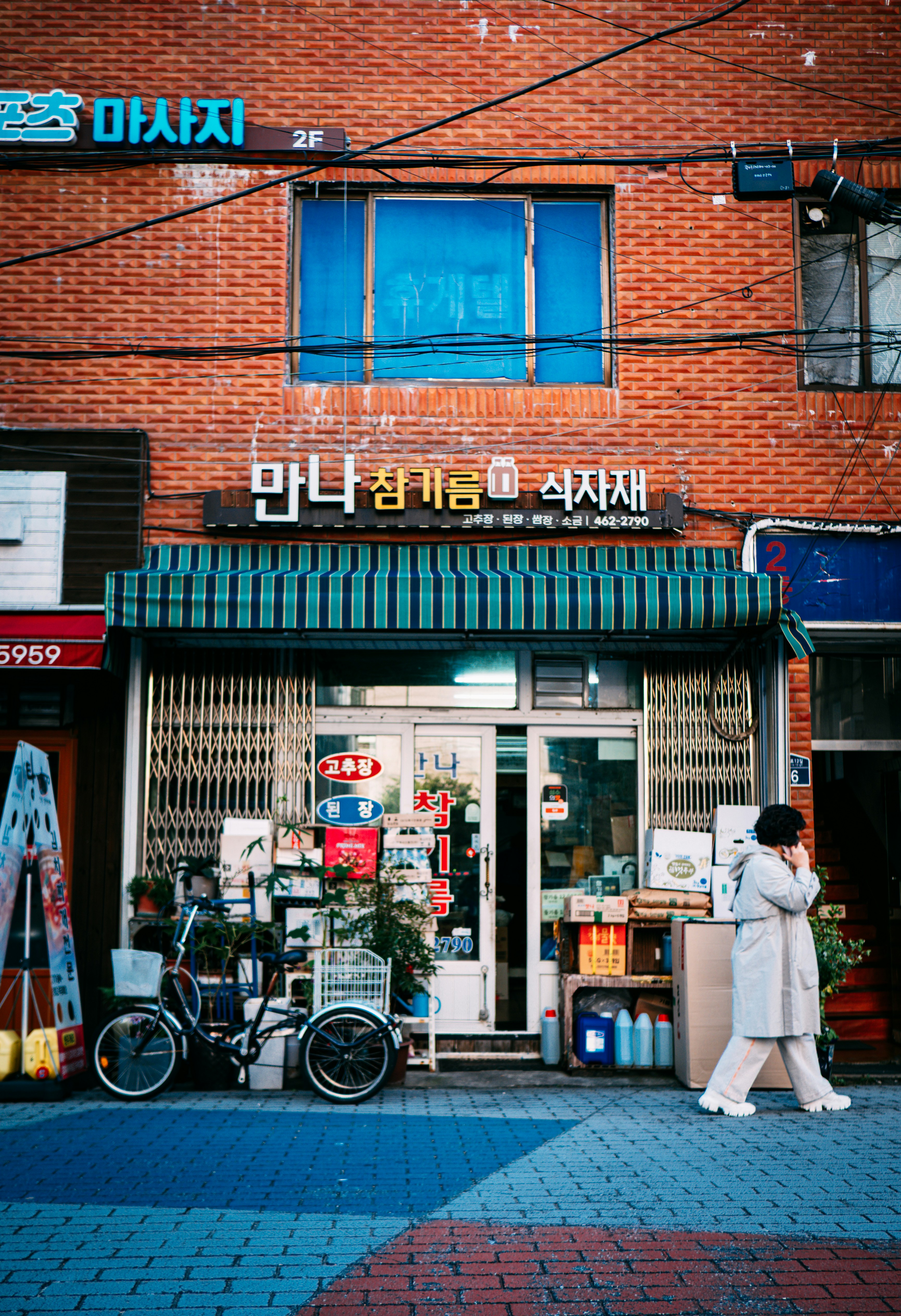 Eine Person geht an einem kleinen Laden vorbei, vor dem Waren stehen.