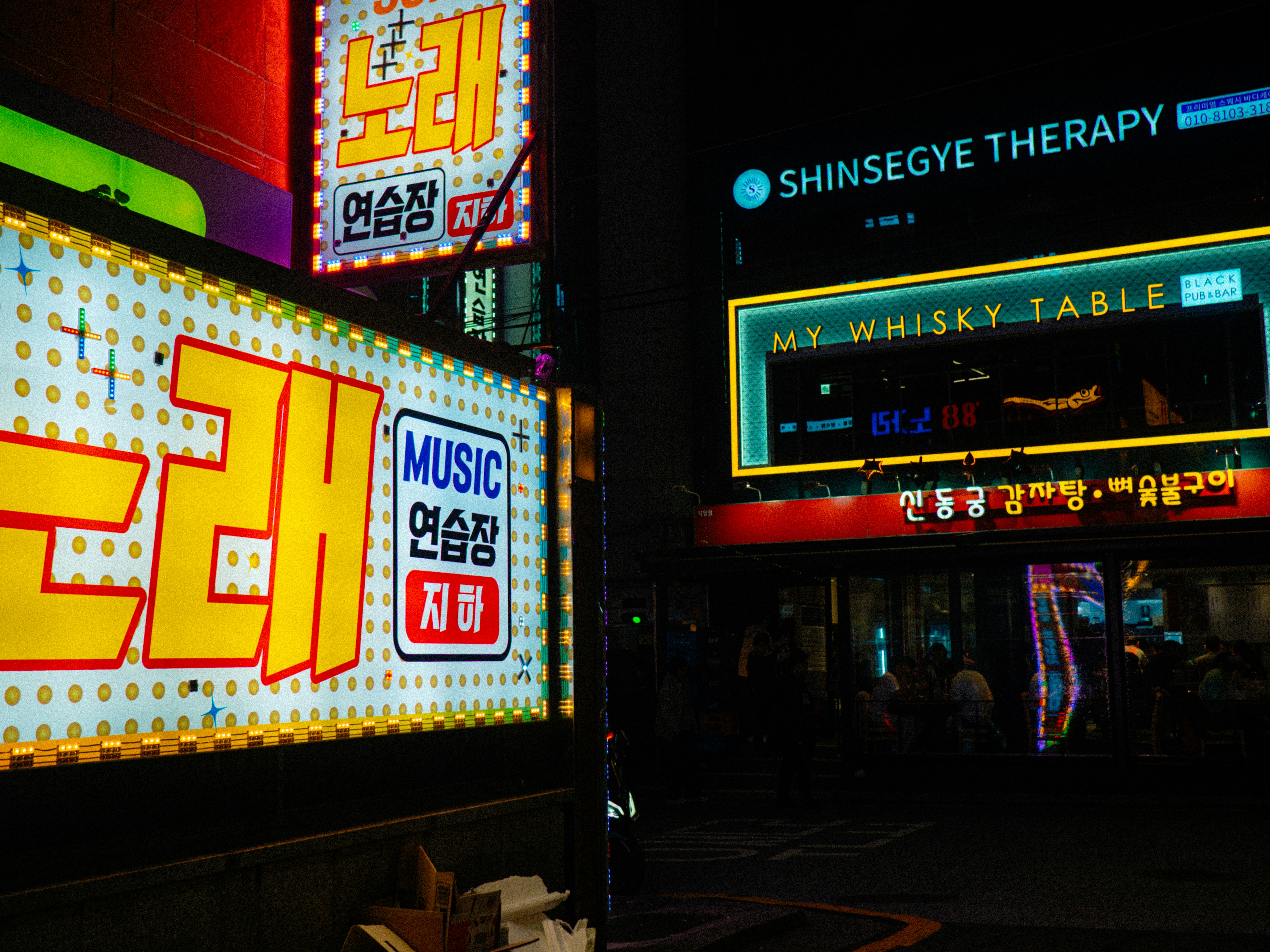Helle Leuchtreklamen erhellen nachts eine Straße in der Stadt.