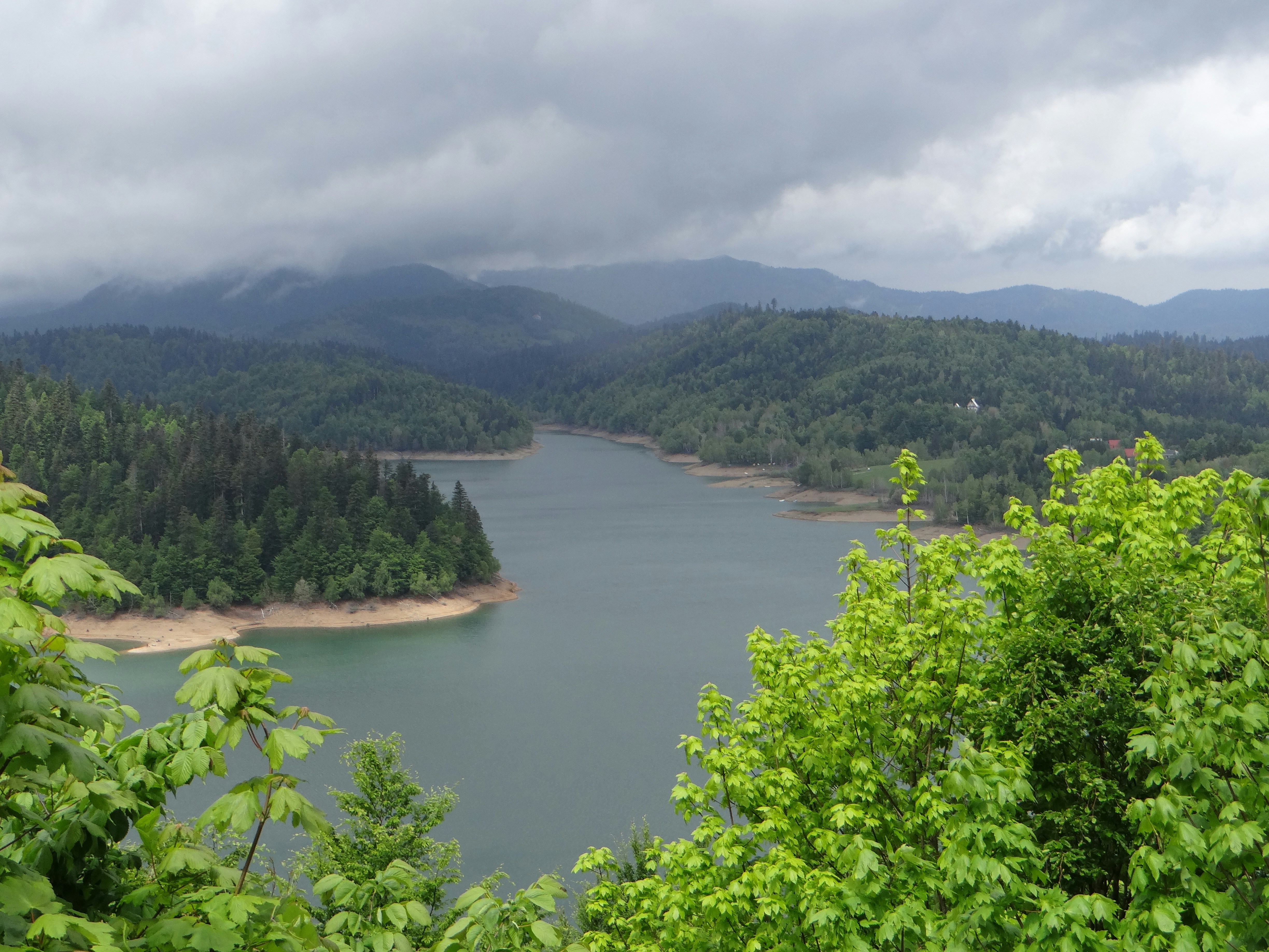 A serene lake surrounded by lush green forested hills.