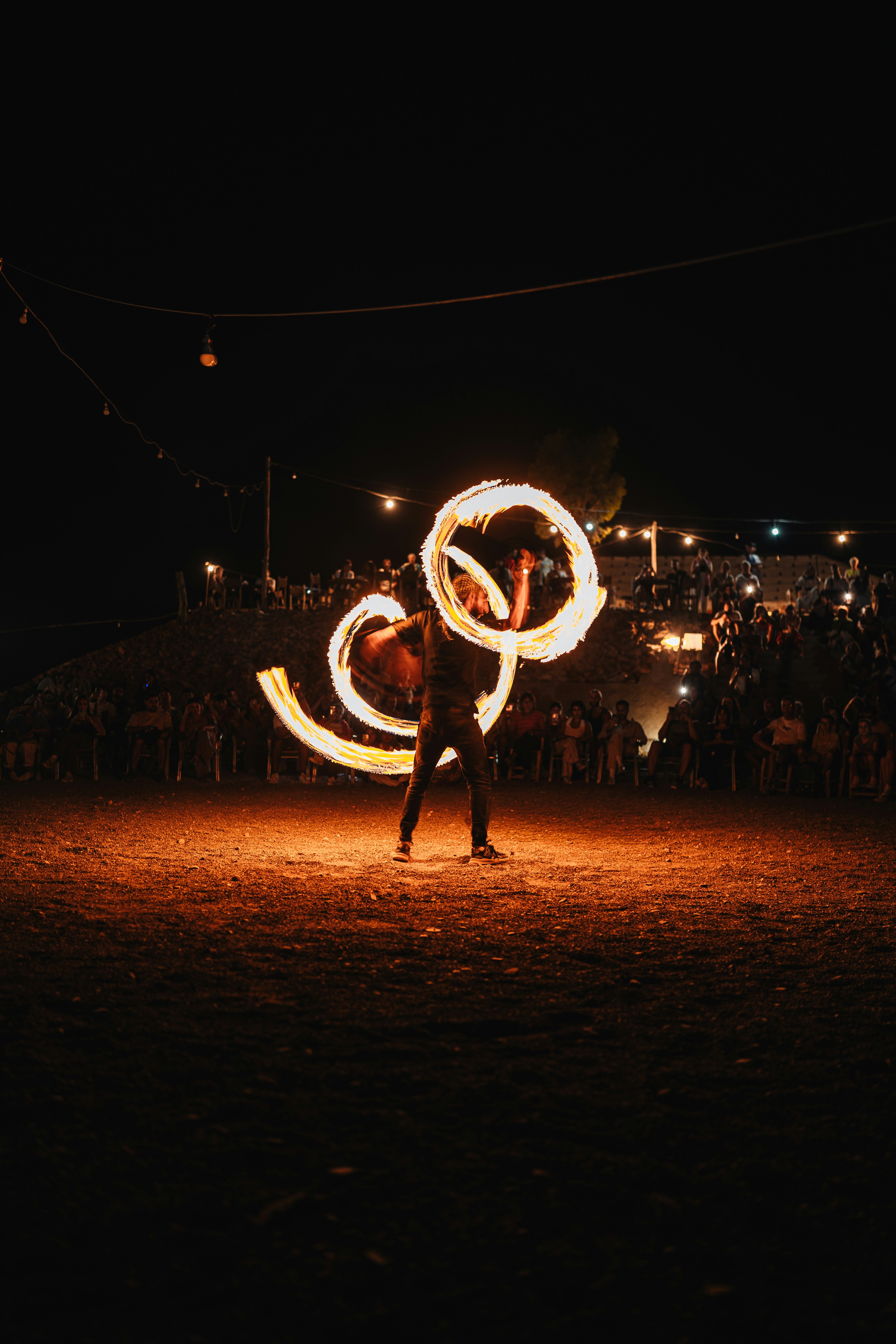 Performer twirls fiery hoops at night event