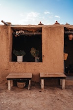 Two wooden benches outside a mud-brick house.
