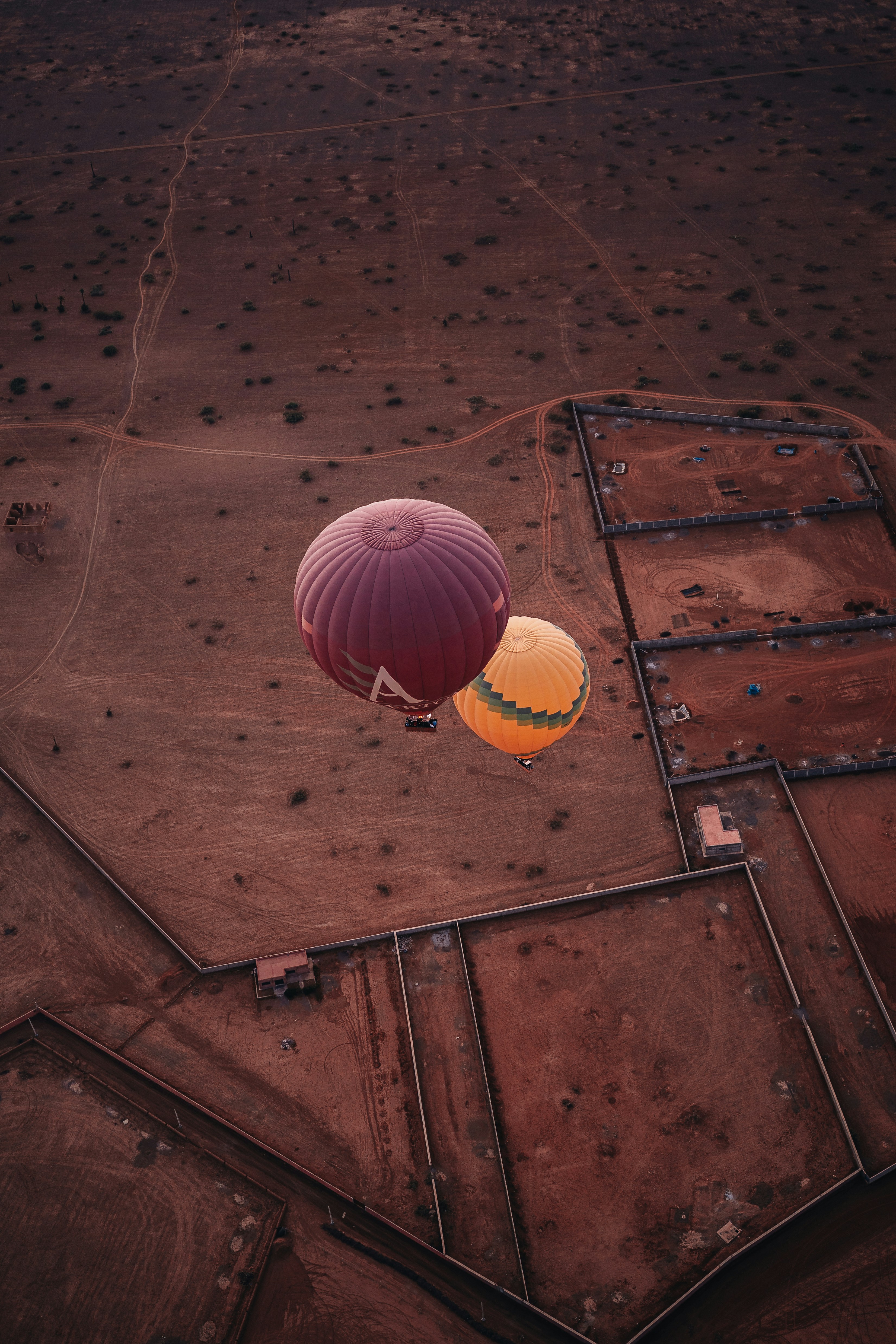Dois balões de ar quente voando sobre uma paisagem rural.