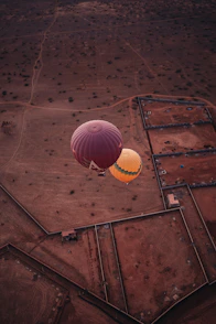 Two hot air balloons flying over a rural landscape
