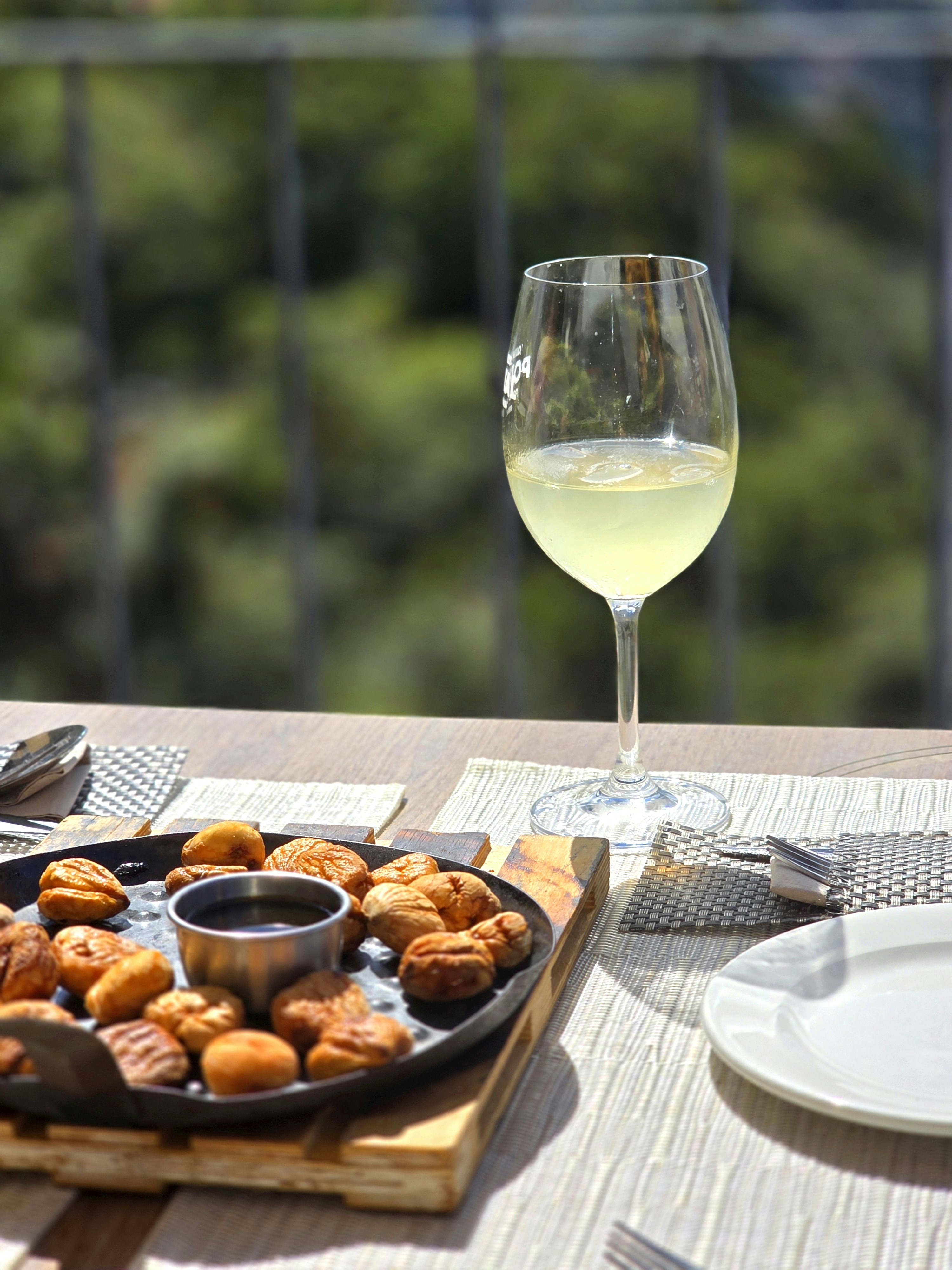 A glass of white wine with appetizers on a table.
