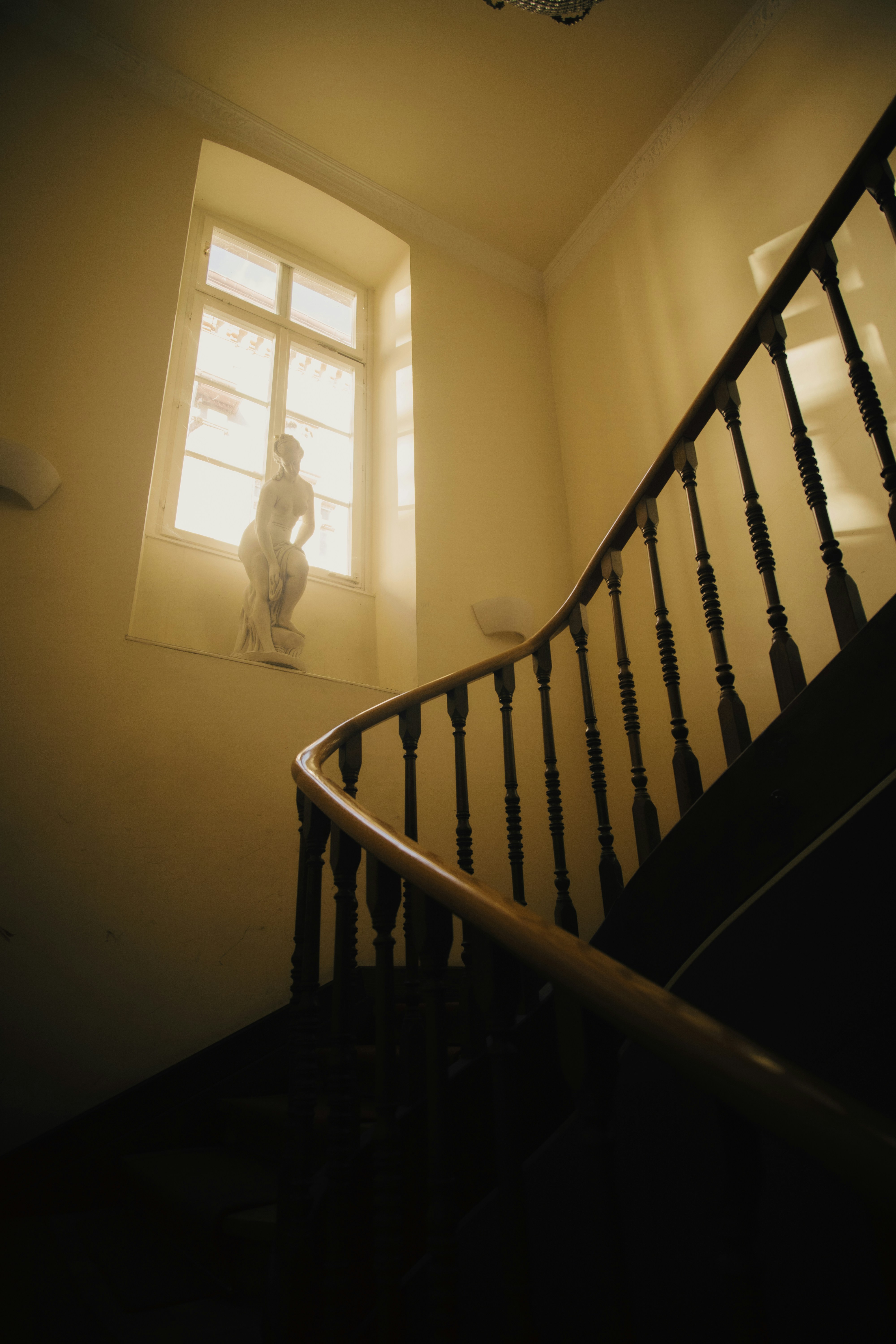 Statue by window next to spiral staircase