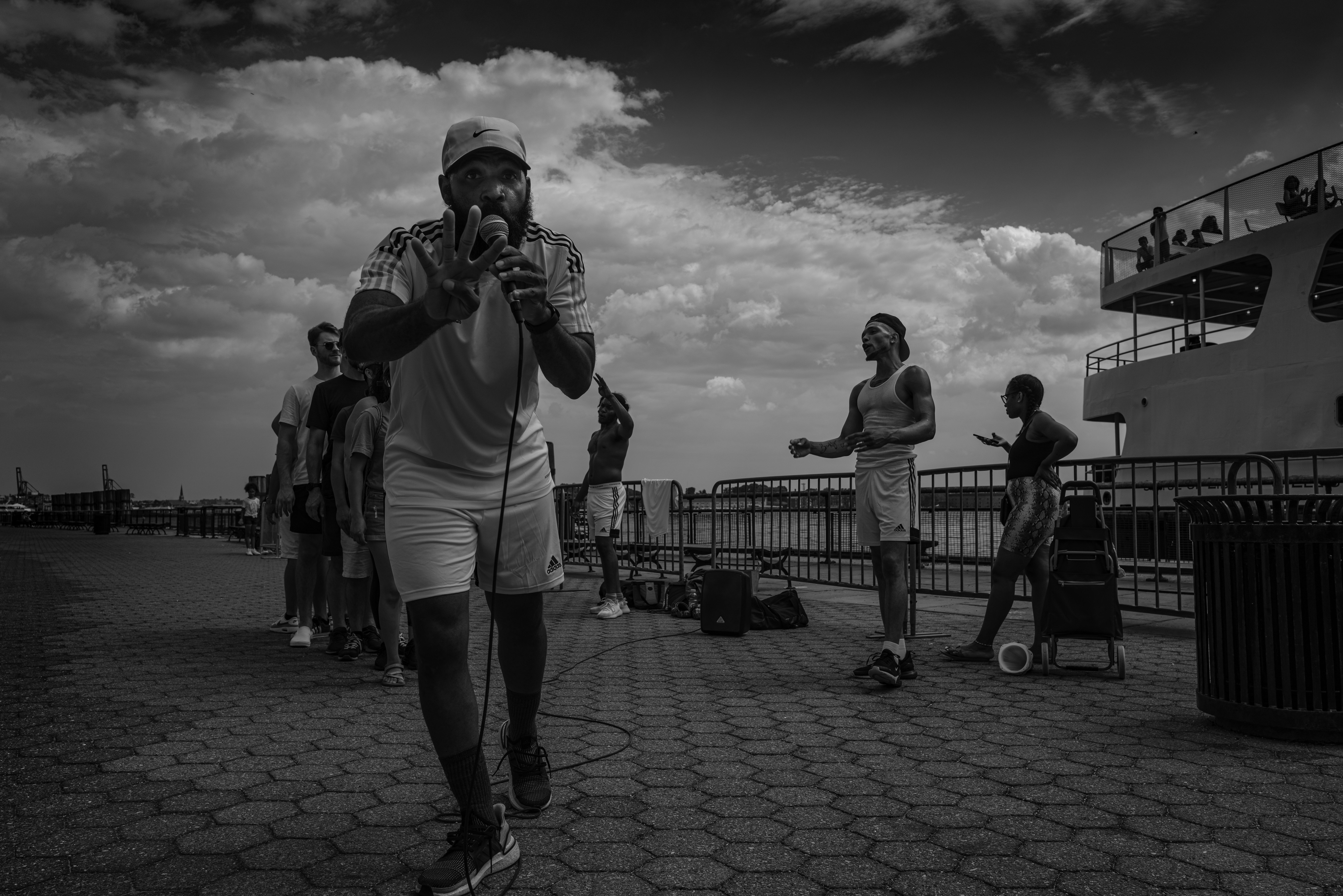 Man with microphone leads group outdoors near water