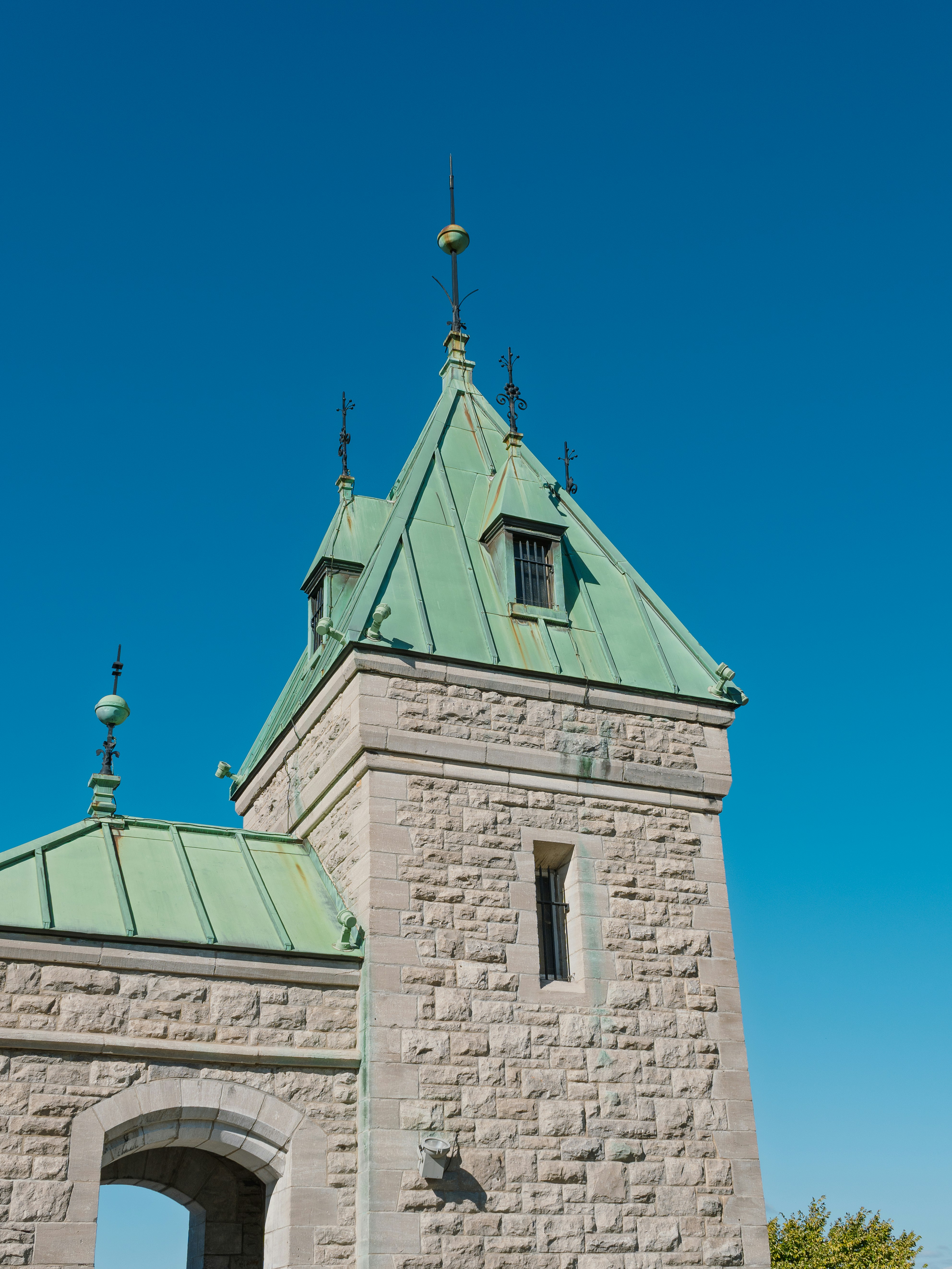 Stone tower with green roof against blue sky