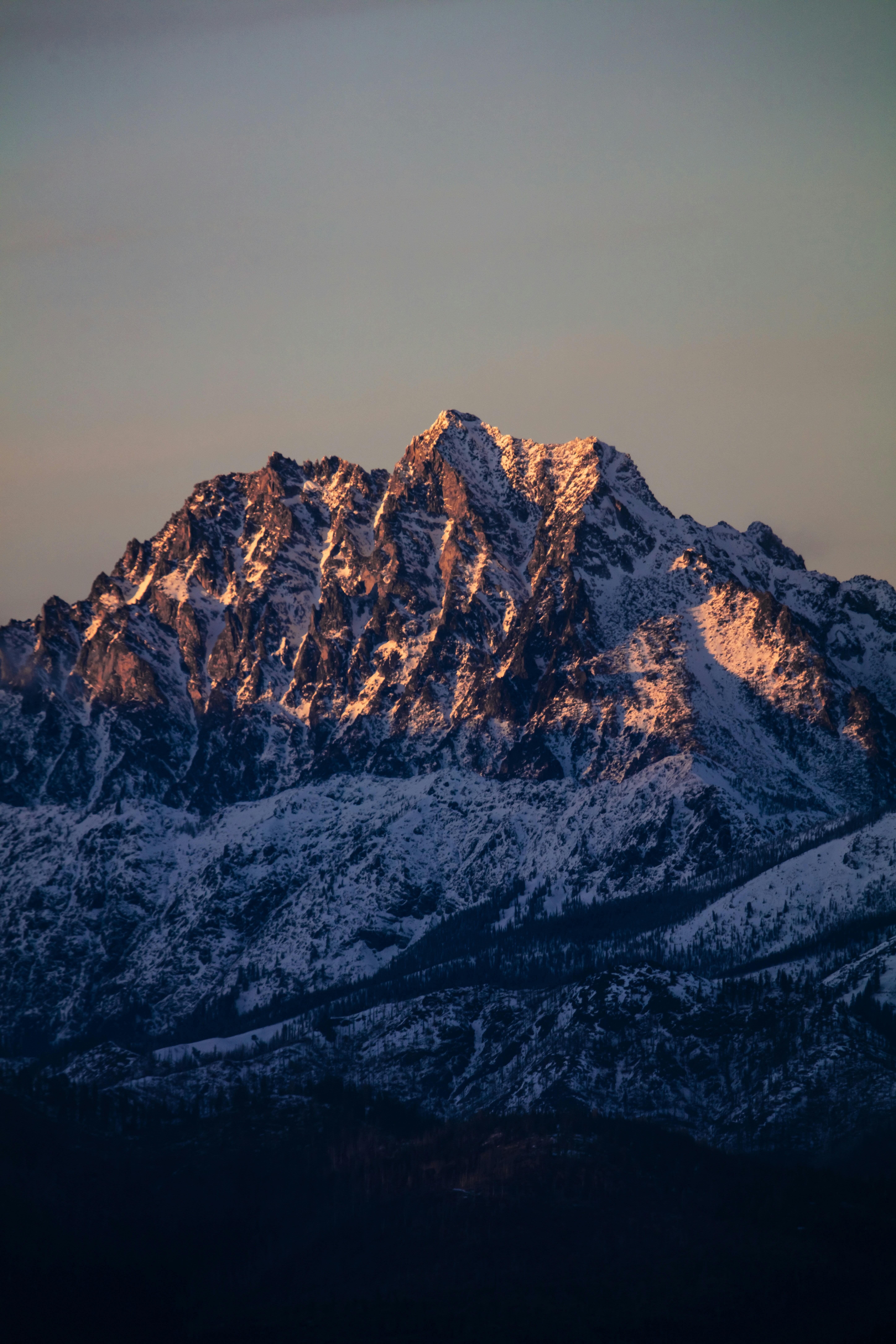 Snow-covered mountain peak illuminated by sunset light