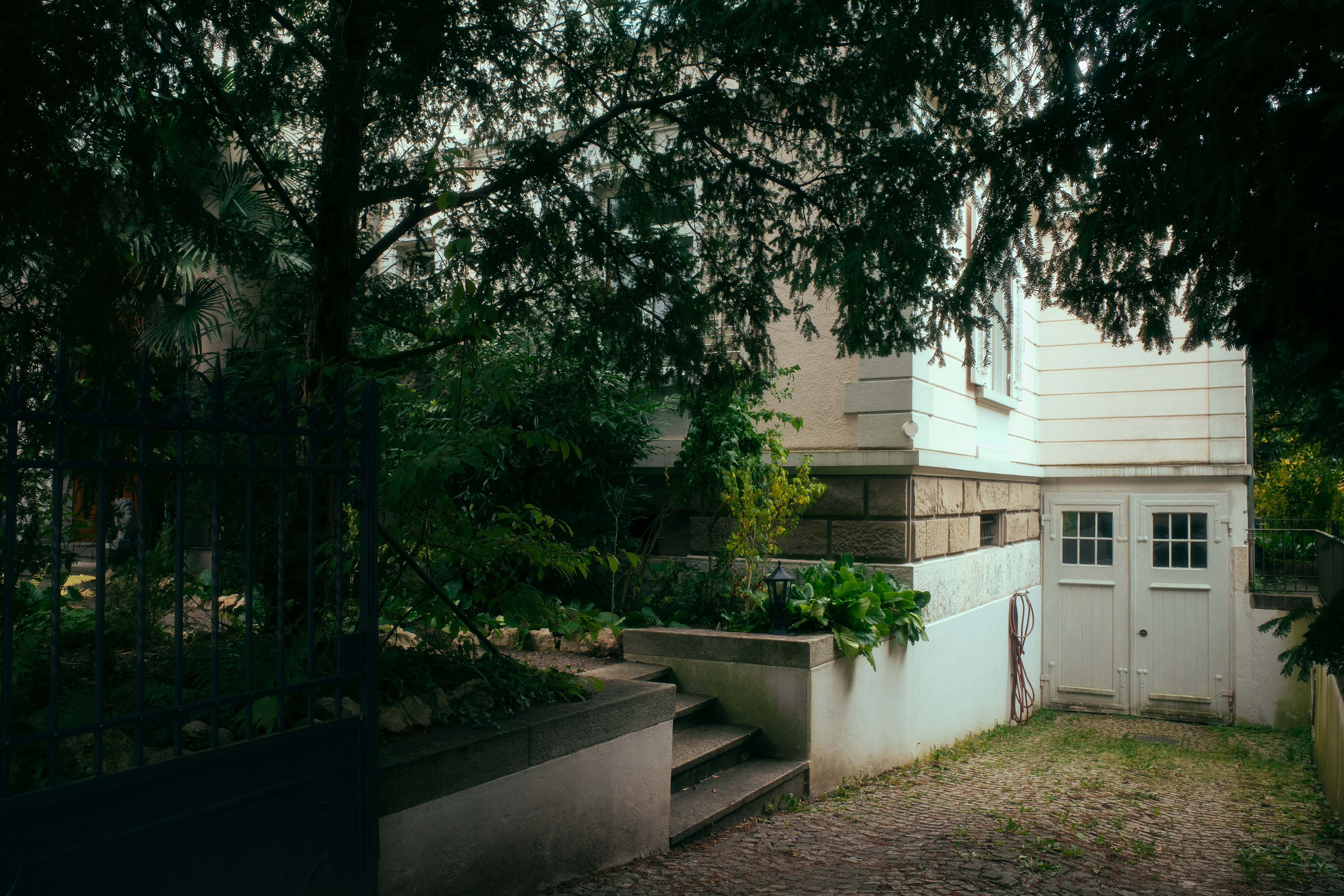 A white house with double doors and green plants