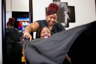 Stylist drapes client with a black cape in salon.