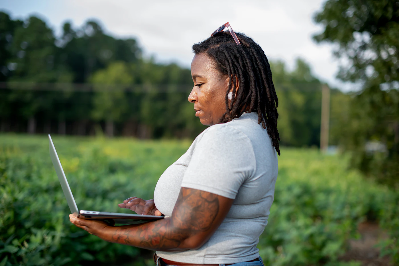 Woman using a laptop in a green field