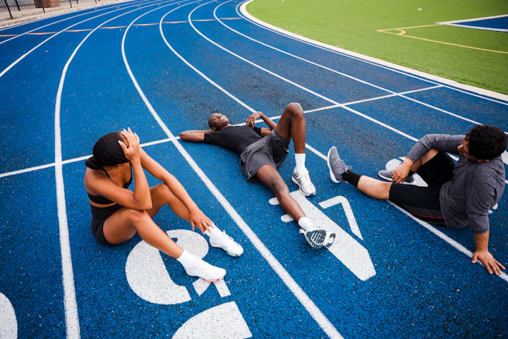 Atletas deitados exaustos na pista após o treino