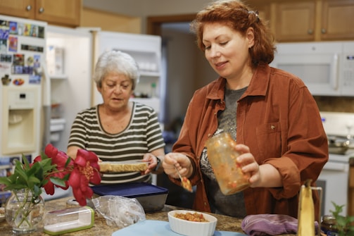 Two women preparing food in a kitchen.