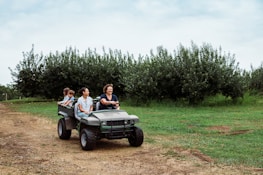 Family riding in a utility vehicle through a field.