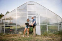 Two people working with a laptop outside greenhouse