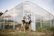 Two people working with a laptop outside greenhouse