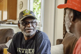 Two men talking, one wears a veteran hat.