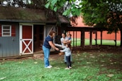Family interacts with a woman near a shed.
