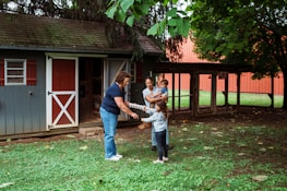 Family interacts with a woman near a shed.