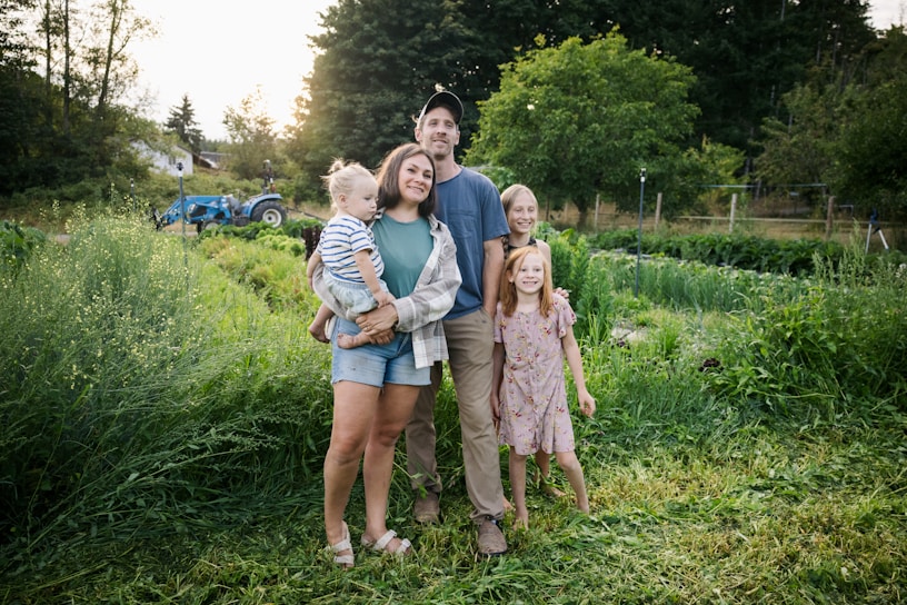 Family standing in a lush green field with tractor.