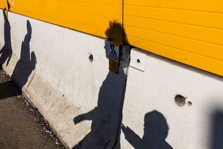 Shadows of people on a concrete barrier