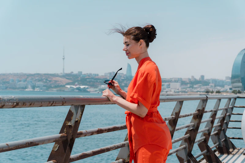 A stylish woman in an orange dress by the water