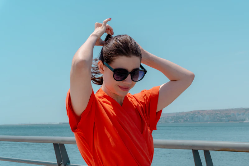 woman in an orange shirt tying her hair