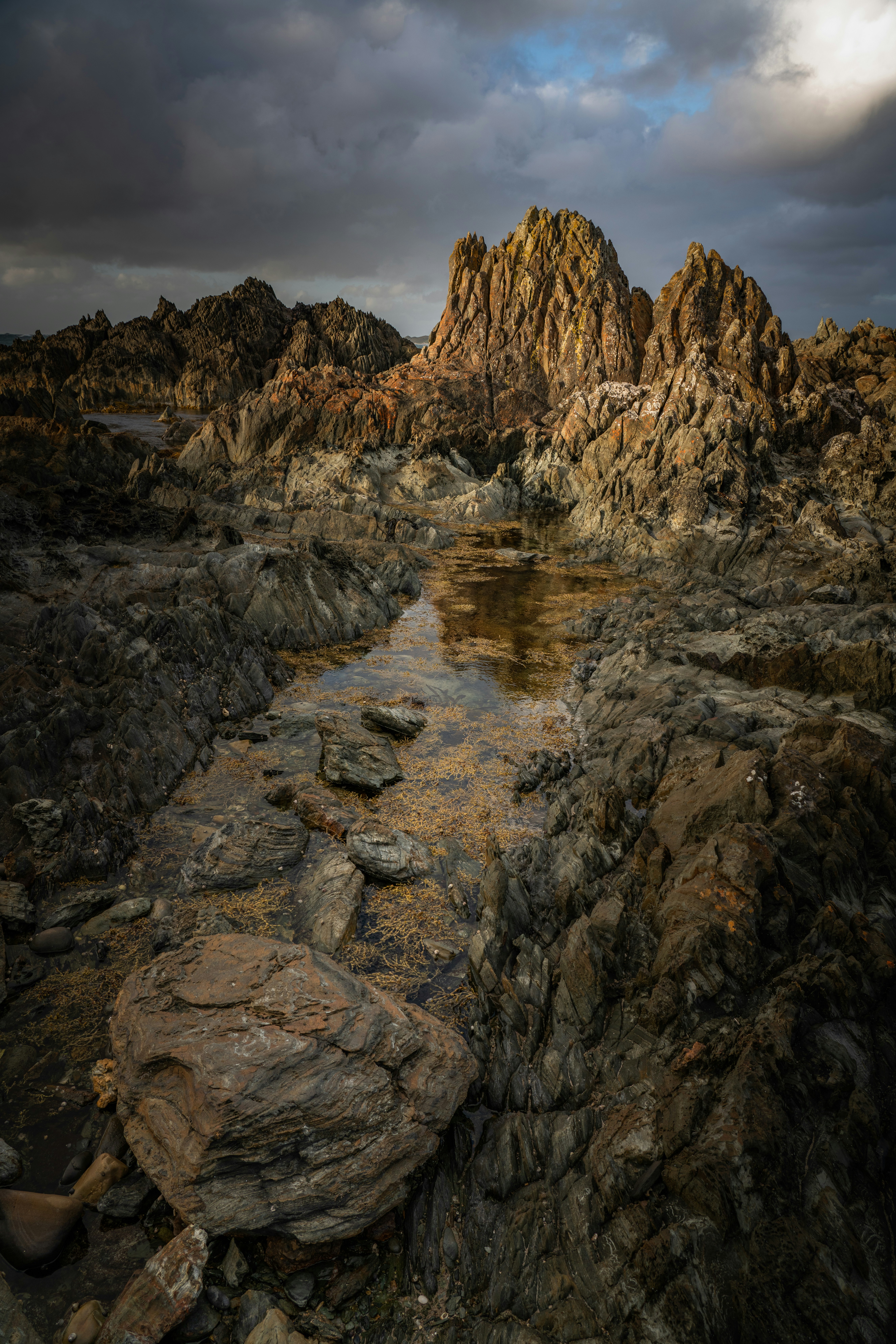 Rocky coastline with dramatic clouds at sunset.