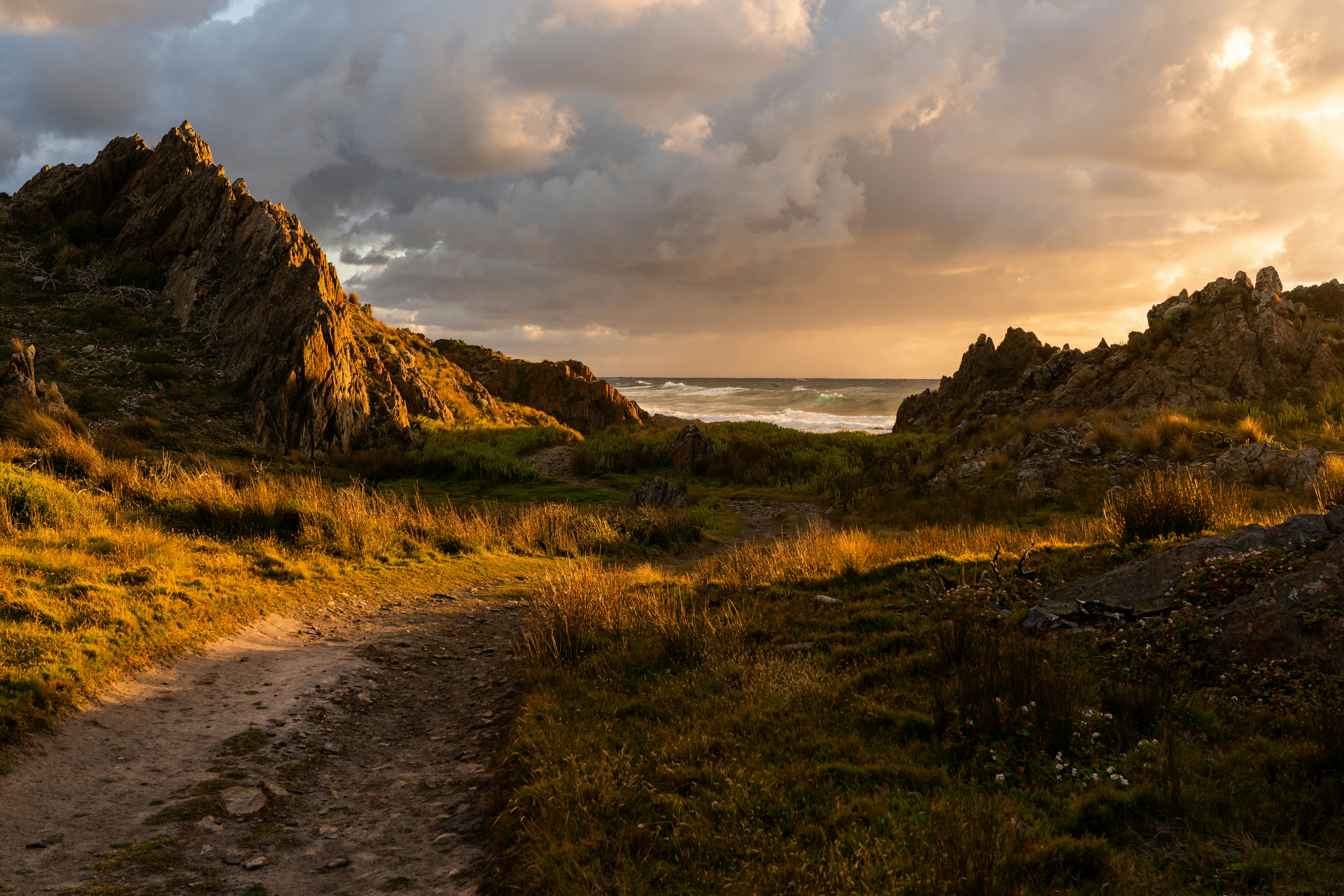 Rocky coastline path at sunset with dramatic clouds