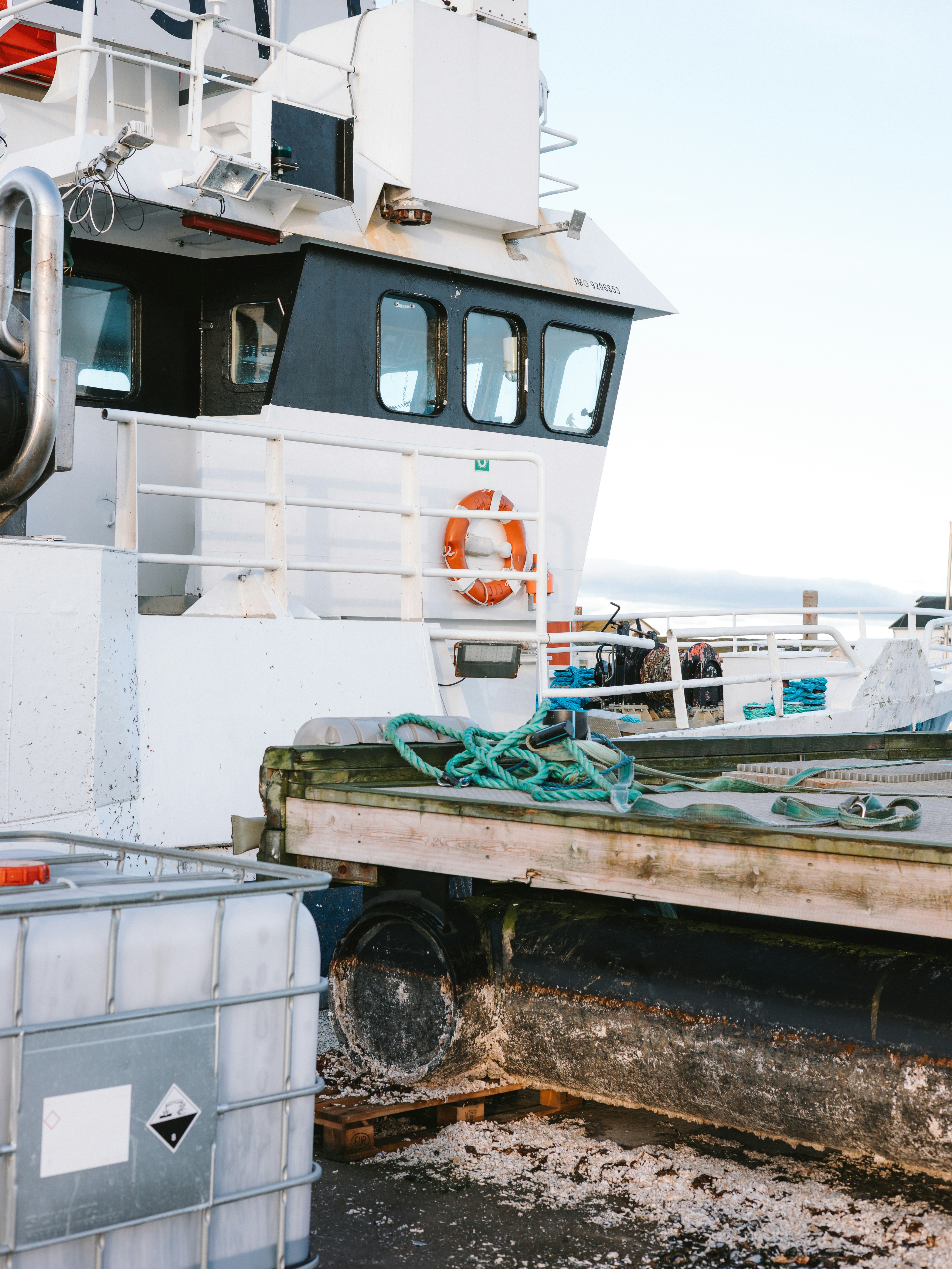 White fishing boat docked at a pier with supplies
