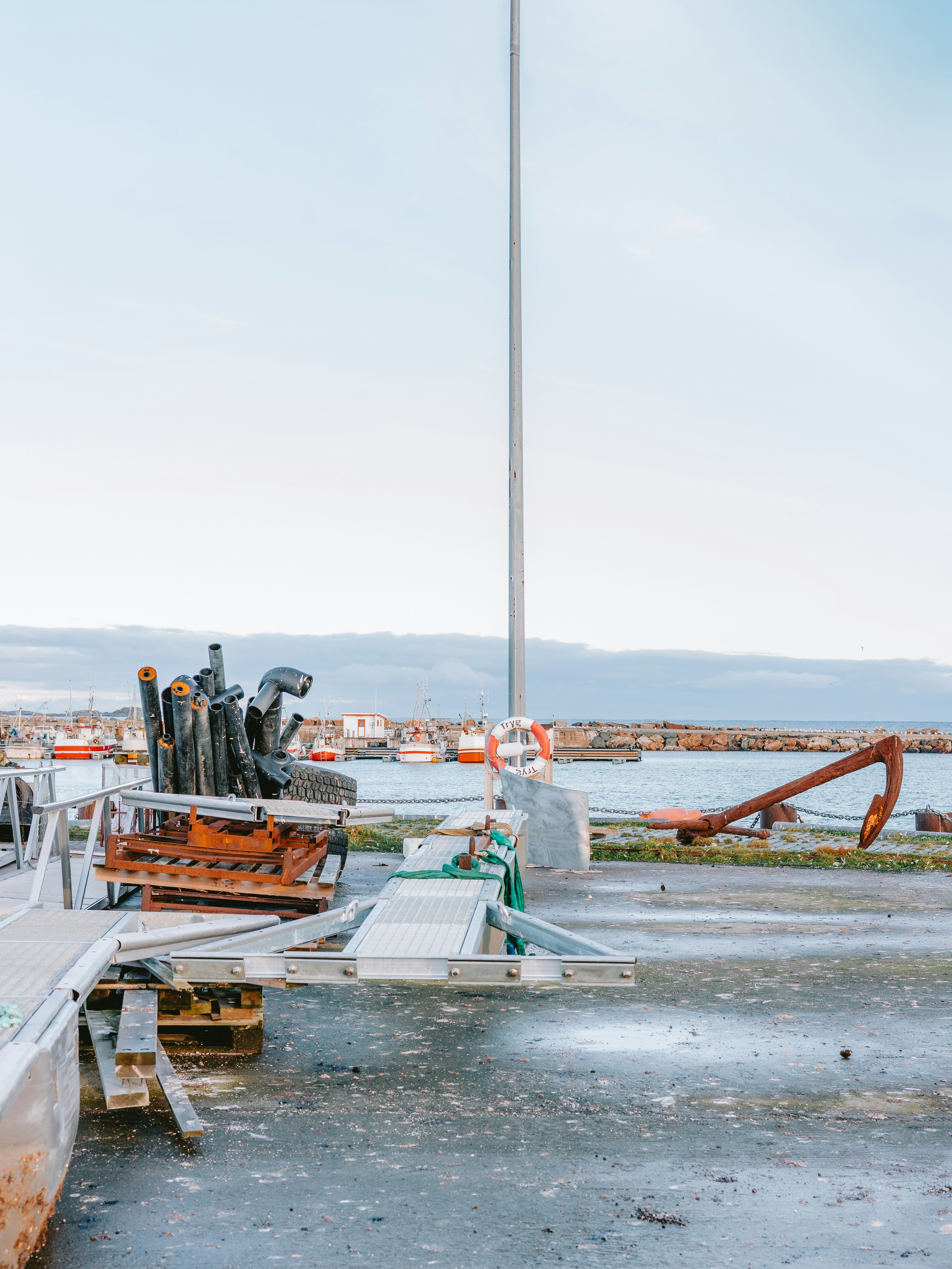 Boats docked at a harbor with industrial equipment
