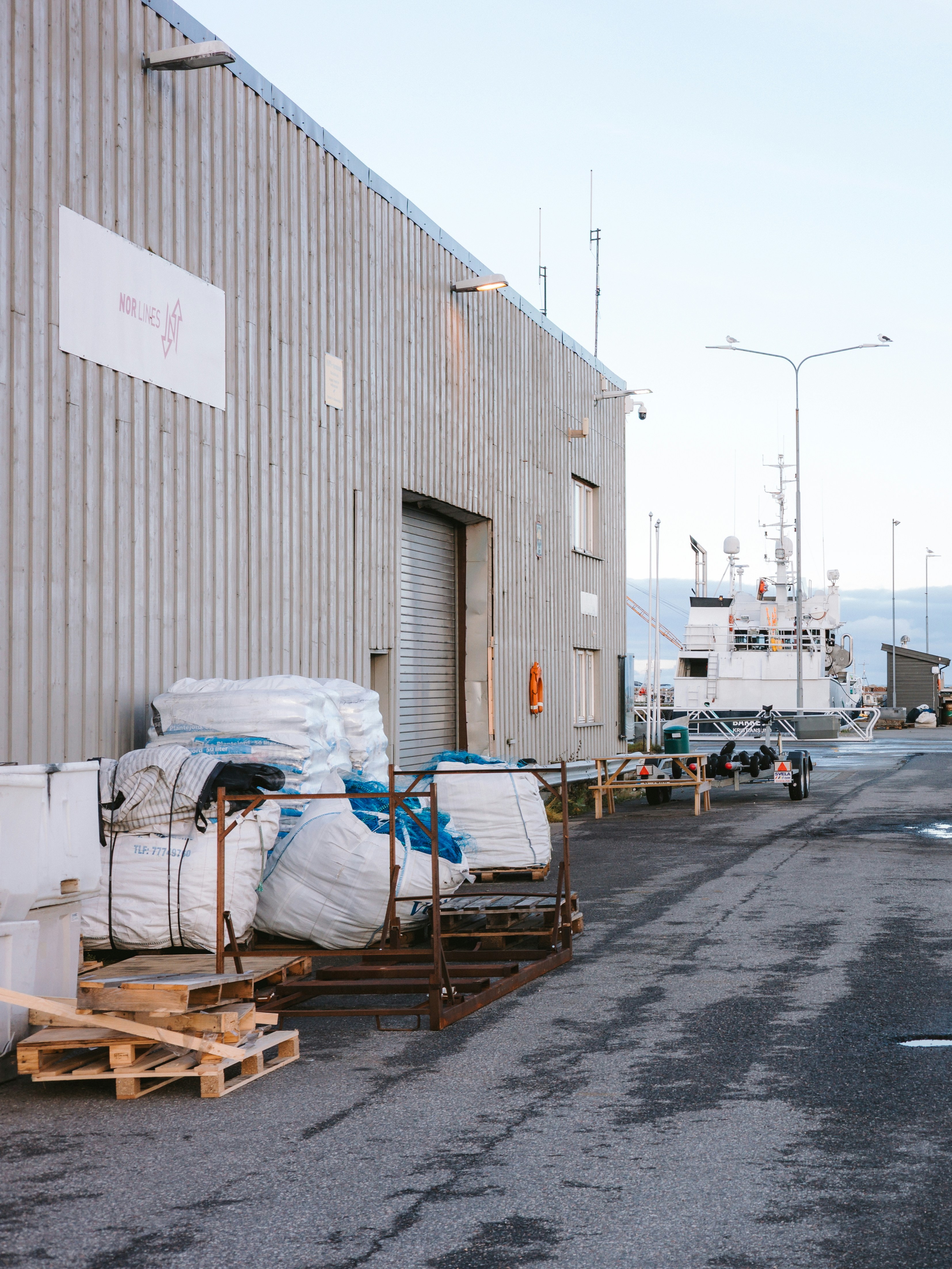 Industrial building with large white sacks and boats nearby