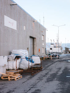 Industrial building with large white sacks and boats nearby