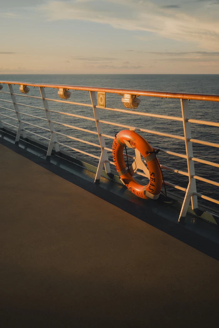 Salvavidas colgado en la baranda de un barco, con el mar al atardecer