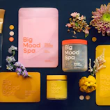Spa products and flowers arranged on dark surface.