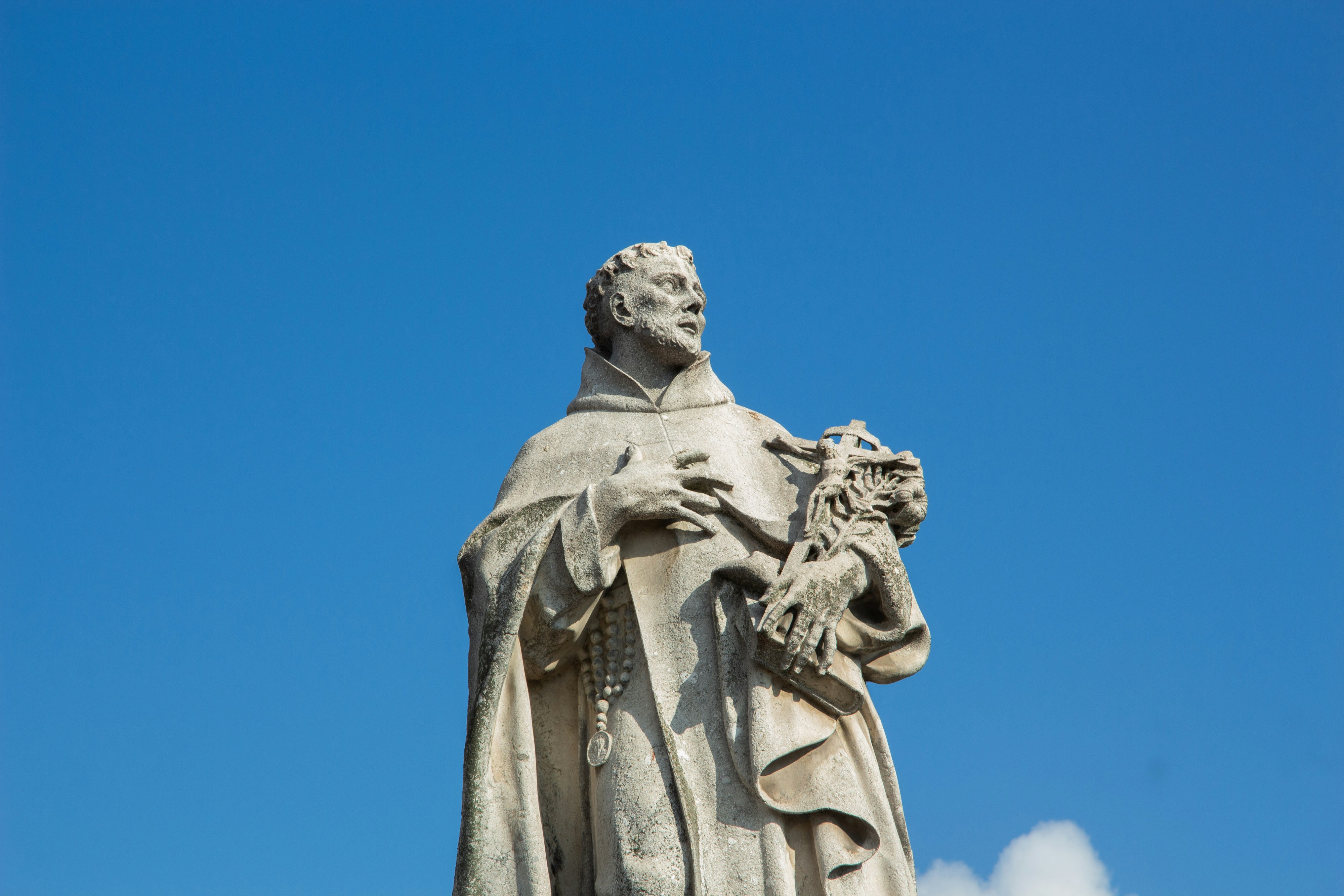 Stone statue of a man in robes against blue sky
