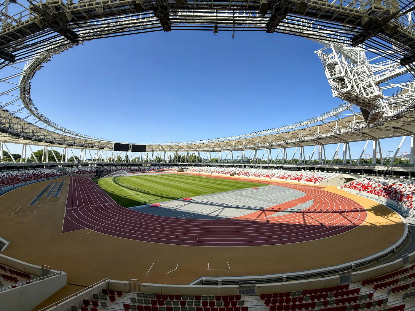 Empty athletics stadium in Budapest with red track lanes and vacant seating, no athletes in frame