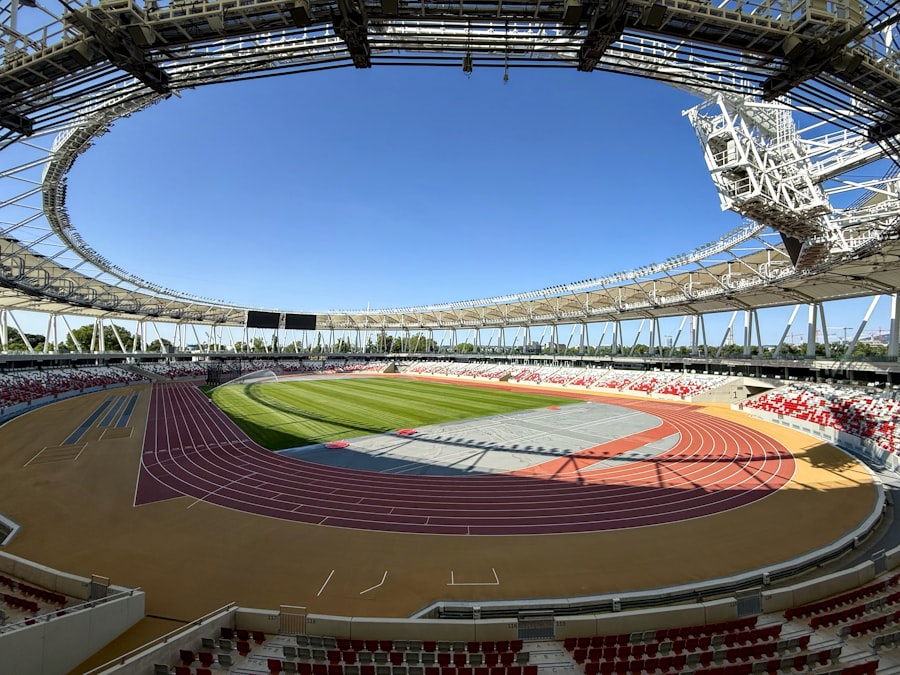 Empty athletics stadium with red track lanes and vacant seating, no athletes in frame