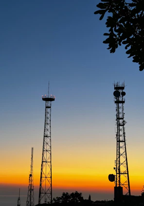 Communication towers silhouetted against a sunset sky