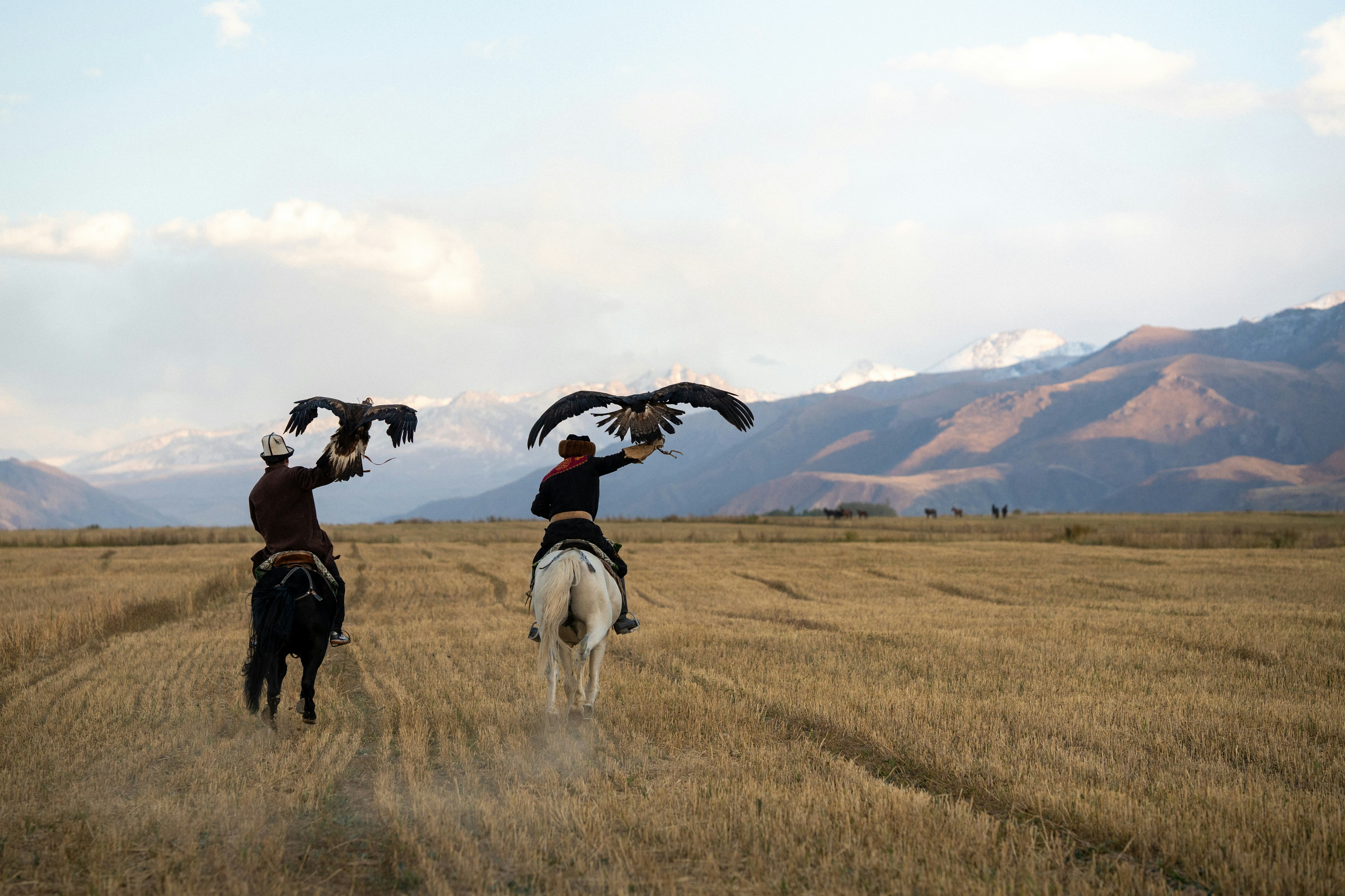 Two people on horseback holding eagles