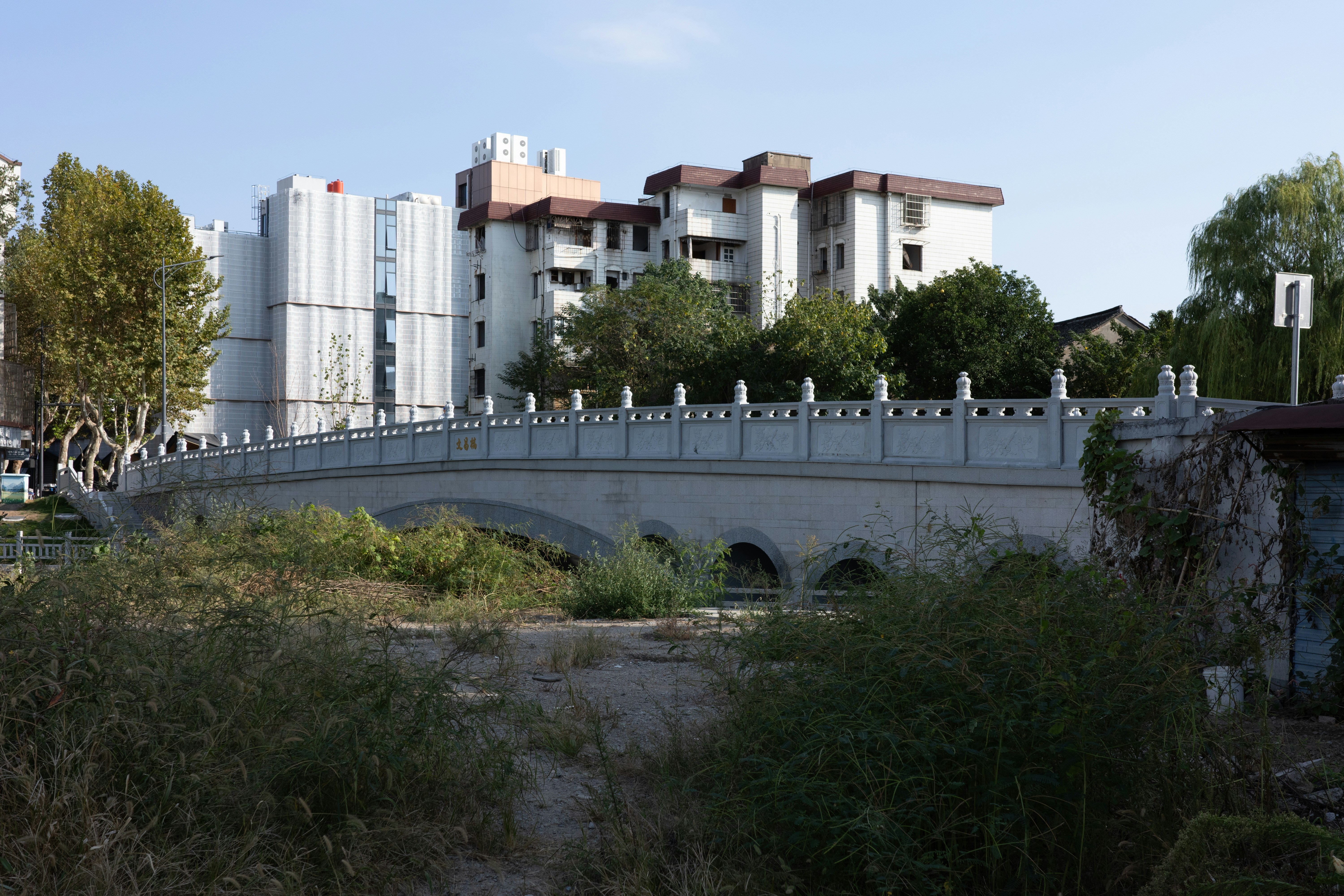 Steinerne Brücke mit verziertem Geländer und dahinter liegenden Gebäuden.