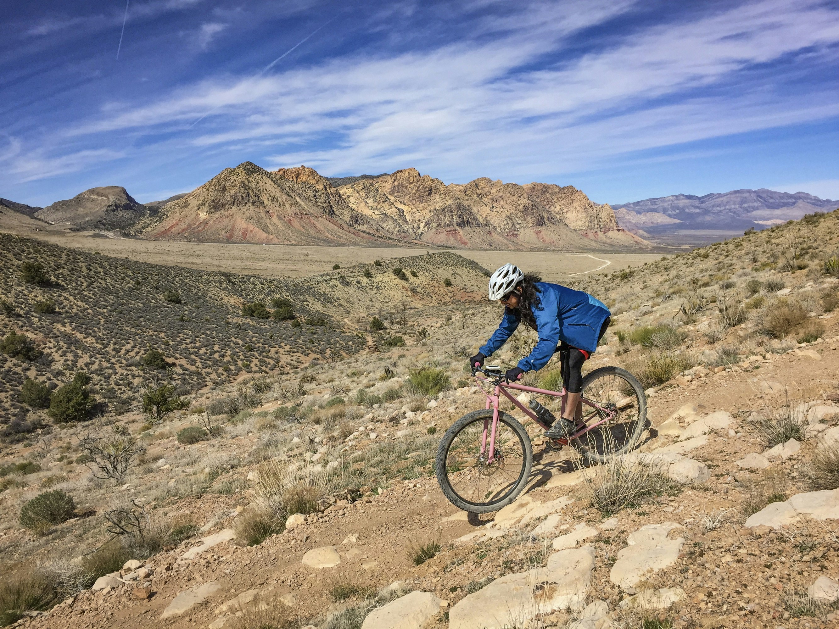 Woman mountain biking downhill on a rocky trail.