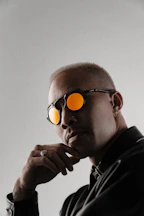 Man wearing sunglasses with orange lenses and thoughtful pose