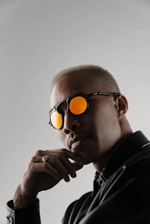 Man wearing sunglasses with orange lenses and thoughtful pose